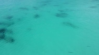 Gök mavisi deniz suyu üzerinde uçmak, dipteki açık deniz suyu ve mercan resifleri, insansız hava aracı görüntüsü.