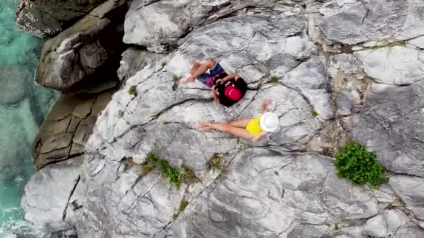 一对夫妇在亚洲旅行 一对夫妇坐在一个热带岛屿的岩石海岸上 从空中观看自己的生活 — 图库视频影像