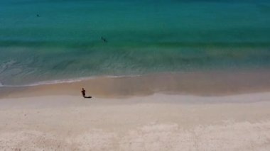 Phuket, Tayland, 21 Ocak 2022, plaj boyunca bir adam yürüyor, tropik bir adanın kıyısındaki kıyı bölgesinin yüksekliğinden bir manzara.