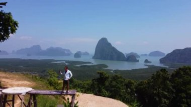 Bir adam, Phang Nga Körfezi 'nin uçurumlarına karşı bir platformda duruyor.