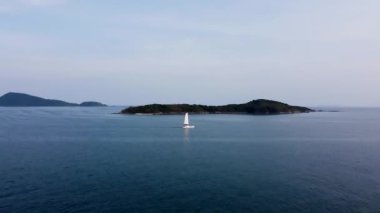 Açık yelkenli yelkenli bir katamaran tropik bir ada boyunca yol alır. Tropiklerdeki bir yelkenli teknesinin havadan görünüşü.