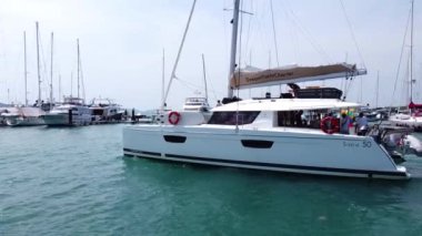 Yelkenli katamaran bir deniz yolculuğuna çıkıyor, yelkenli limandan ayrılıyor.