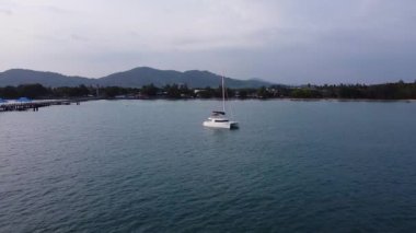 Bir yelkenli katamaran tropikal bir adanın yakınına demir atar. Tropiklerde bir yelkenli, hava manzaralı.