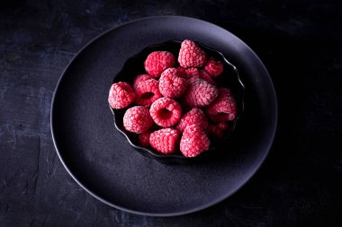 Kasede ahududu ve siyah arka plan. Donmuş meyve. Donmuş ahududu karamsar fotoğrafı