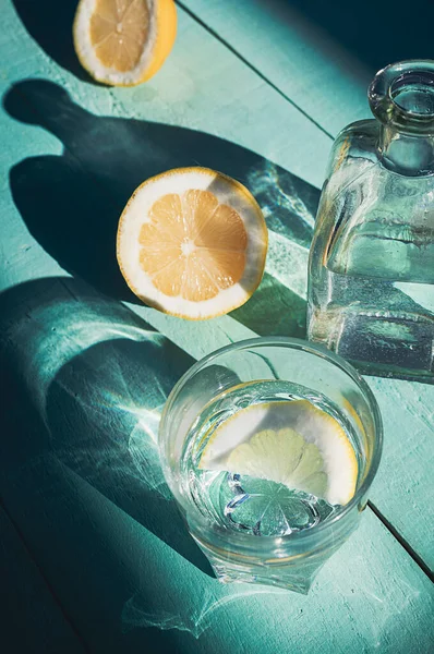 Turkuaz ahşap arka planda limonlu su. C vitamini detoks içeceğiyle iç.