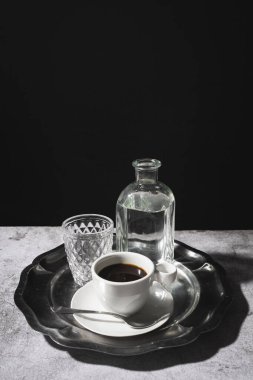 Sade kahve ve bir bardak su zarif gümüş tepside koyu arkaplan