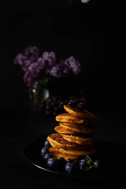 Akçaağaç şurubu ve taze yaban mersinli ev yapımı krepler. Ev yapımı ve koyu arkaplanı olan sağlıklı bir kahvaltı. Glütensiz havuçlu krep.