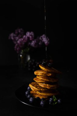 Akçaağaç şurubu ve taze yaban mersinli ev yapımı krepler. Ev yapımı ve koyu arkaplanı olan sağlıklı bir kahvaltı. Glütensiz havuçlu krep.