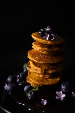 Akçaağaç şurubu ve taze yaban mersinli ev yapımı krepler. Ev yapımı ve koyu arkaplanı olan sağlıklı bir kahvaltı. Glütensiz havuçlu krep.