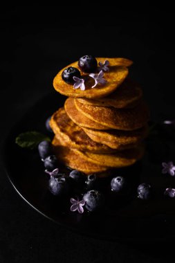 Akçaağaç şurubu ve taze yaban mersinli ev yapımı krepler. Ev yapımı ve koyu arkaplanı olan sağlıklı bir kahvaltı. Glütensiz havuçlu krep.