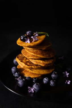 Akçaağaç şurubu ve taze yaban mersinli ev yapımı krepler. Ev yapımı ve koyu arkaplanı olan sağlıklı bir kahvaltı. Glütensiz havuçlu krep.