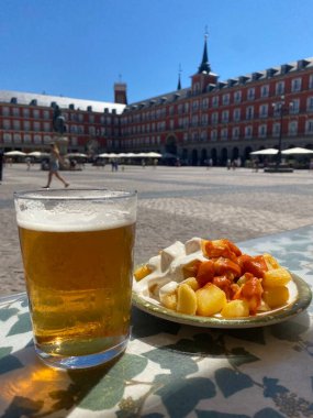 A portion of tapas in the Plaza Mayor in Madrid. Potatoes with alioli sauce and brava sauce with a beer. Typical Madrid tapas