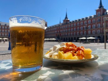 A portion of tapas in the Plaza Mayor in Madrid. Potatoes with alioli sauce and brava sauce with a beer. Typical Madrid tapas