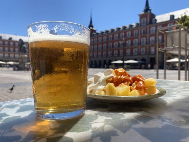 A portion of tapas in the Plaza Mayor in Madrid. Potatoes with alioli sauce and brava sauce with a beer. Typical Madrid tapas