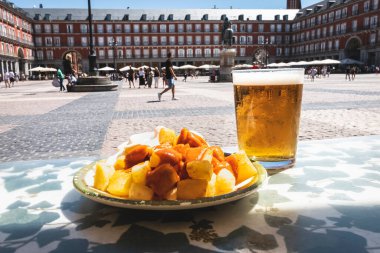A portion of tapas in the Plaza Mayor in Madrid. Potatoes with alioli sauce and brava sauce with a beer. Typical Madrid tapas