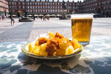 A portion of tapas in the Plaza Mayor in Madrid. Potatoes with alioli sauce and brava sauce with a beer. Typical Madrid tapas