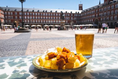 A portion of tapas in the Plaza Mayor in Madrid. Potatoes with alioli sauce and brava sauce with a beer. Typical Madrid tapas