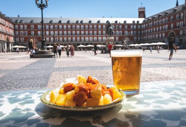 A portion of tapas in the Plaza Mayor in Madrid. Potatoes with alioli sauce and brava sauce with a beer. Typical Madrid tapas
