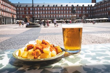 A portion of tapas in the Plaza Mayor in Madrid. Potatoes with alioli sauce and brava sauce with a beer. Typical Madrid tapas