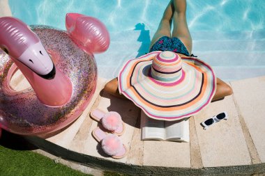 Girl in big hat in the pool. Woman relaxing in a pool of crystal clear and turquoise water. Vacation time