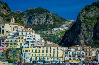 Küçük plajlı ve kayaların üzerinde renkli evleri olan Amalfi köyünün güzel manzarası. Amalfi kıyısındaki dağların tepeleri, Salerno, Campania, İtalya mavi gökyüzü ve güzel hava