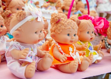 Caddedeki bir dükkanda rengarenk giysiler içinde güzel bebekler.