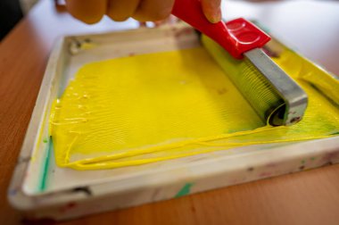 Boya yapmadan önce bir işçinin elindeki tepside hazırlanmış sarı boya rulosu.