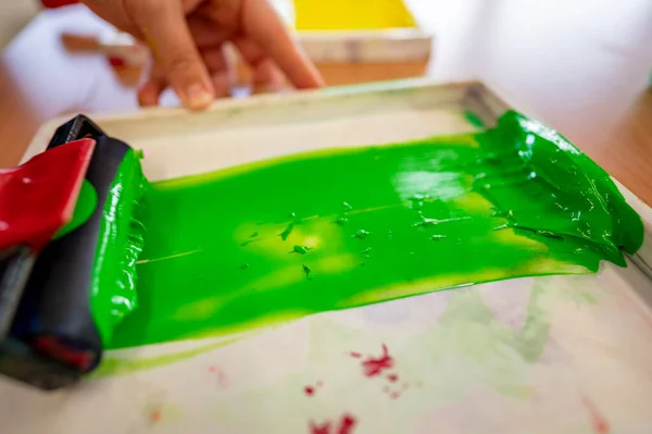 Roll of green paint prepared in a tray in a worker\'s hand before painting