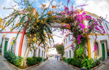3 Şubat 2022 Puerto de Mogan Kanarya Adası İspanya Pembe kırmızı ve turuncu çiçekli dar sokaklarla dolu bir kasaba zemin kattaki dükkanları turistler tarafından ziyaret edilen renkli binalarla dolu.