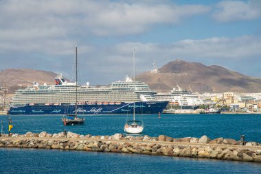 4 Şubat 2022 - Las Palmas Kanarya Adası limanının ön planda bazı turistler denizden geri dönüyorlar, arka planda büyük bir istiridye gemisi