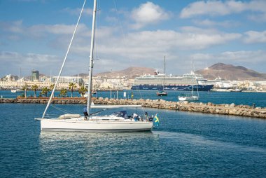 4 Şubat 2022 - Las Palmas Kanarya Adası limanının ön planda bazı turistler denizden geri dönüyorlar, arka planda büyük bir istiridye gemisi