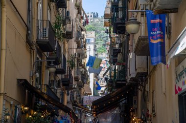 April 9 2022- Naples Italy street with small shops typical for napoli at a window is approached Ukraine's flag