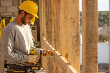 Erkek müteahhit çatıda çalışır, kıvrımlı çarşafları bağlar.