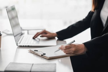 İş kadınının not alıp ofisteki bilgisayarı kullanırken yakın plan fotoğrafı..