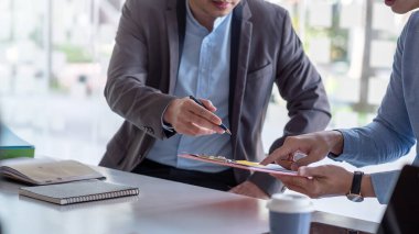 İş adamı toplantısı ofiste grafiğe işaret eden çalışma fikirlerini paylaşıyor.