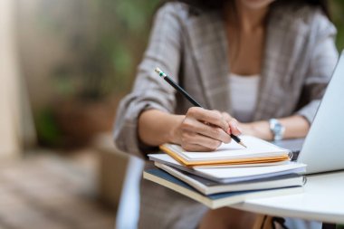 Masada dizüstü bilgisayarla not alan genç bir kadının fotoğrafını çek..