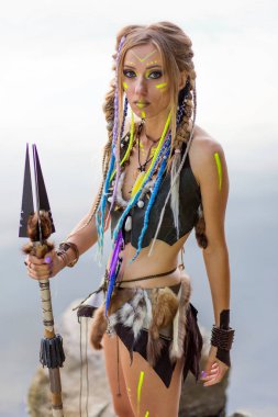 Ortaçağ kürklü, savaş boyalı, ormanda nehrin arka planında mızraklı güzel amazon kadın..