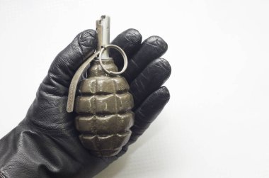 Bir eğitim bombasını tutan eldivenli el, beyaz arka planda yakın plan.