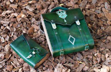 Çantanın içinde yeşil deri bir cüzdan var, ağaç kabuğunun arkasında. 