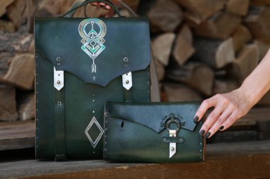 Yeşil deri cüzdanı olan sırt çantası, yakacak odununun arka planında.