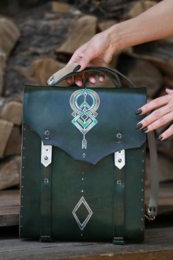 Kadının elinde yeşil deri ve ahşaptan yapılmış bir çanta var.