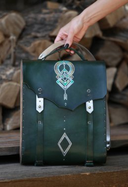 Kadının elinde yeşil deri ve ahşaptan yapılmış bir çanta var.