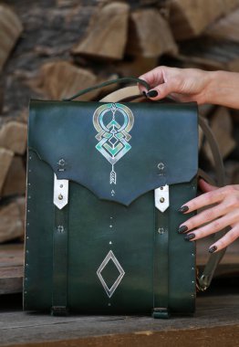 Kadının elinde yeşil deri ve ahşaptan yapılmış bir çanta var.