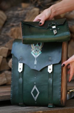 Yeşil deri cüzdanı olan sırt çantası, yakacak odununun arka planında.