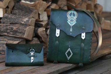 Yeşil deri cüzdanı olan sırt çantası, yakacak odununun arka planında.