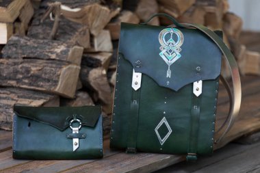 Yeşil deri cüzdanı olan sırt çantası, yakacak odununun arka planında.