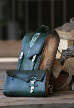 Yeşil deri cüzdanı olan sırt çantası, yakacak odununun arka planında.