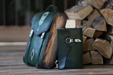 Yeşil deri cüzdanı olan sırt çantası, yakacak odununun arka planında.