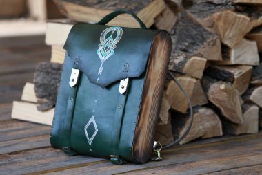 Yeşil deri cüzdanı olan sırt çantası, yakacak odununun arka planında.