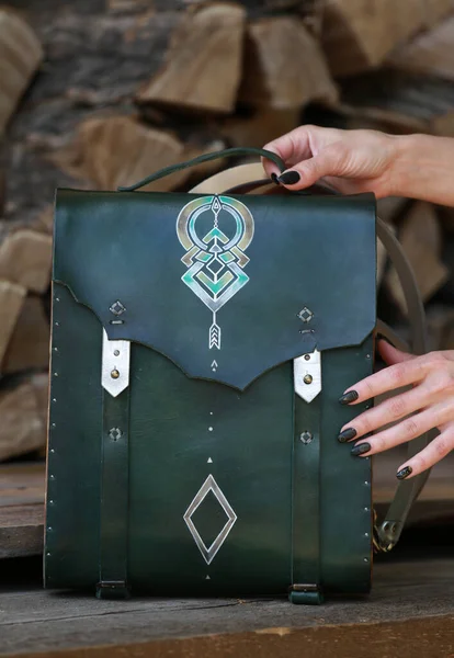 Kadının elinde yeşil deri ve ahşaptan yapılmış bir çanta var.